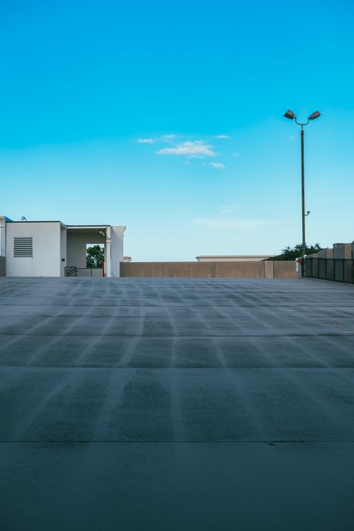 Free Contemporary urban building with an open driveway under a clear blue sky, emphasizing modern design. Stock Photo
