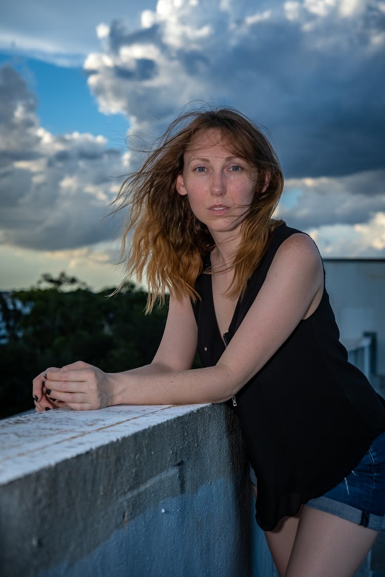 Portrait Of A Woman Standing On A Balcony During Blowing Wind