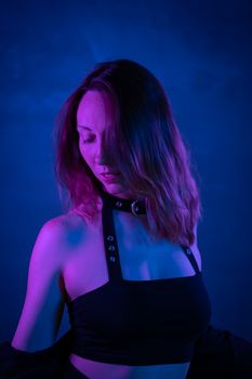 Fashion model posing under striking neon blue and purple lighting, creating a moody atmosphere.