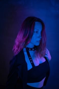 A stylish woman poses in neon blue and purple lighting, creating a moody atmosphere.