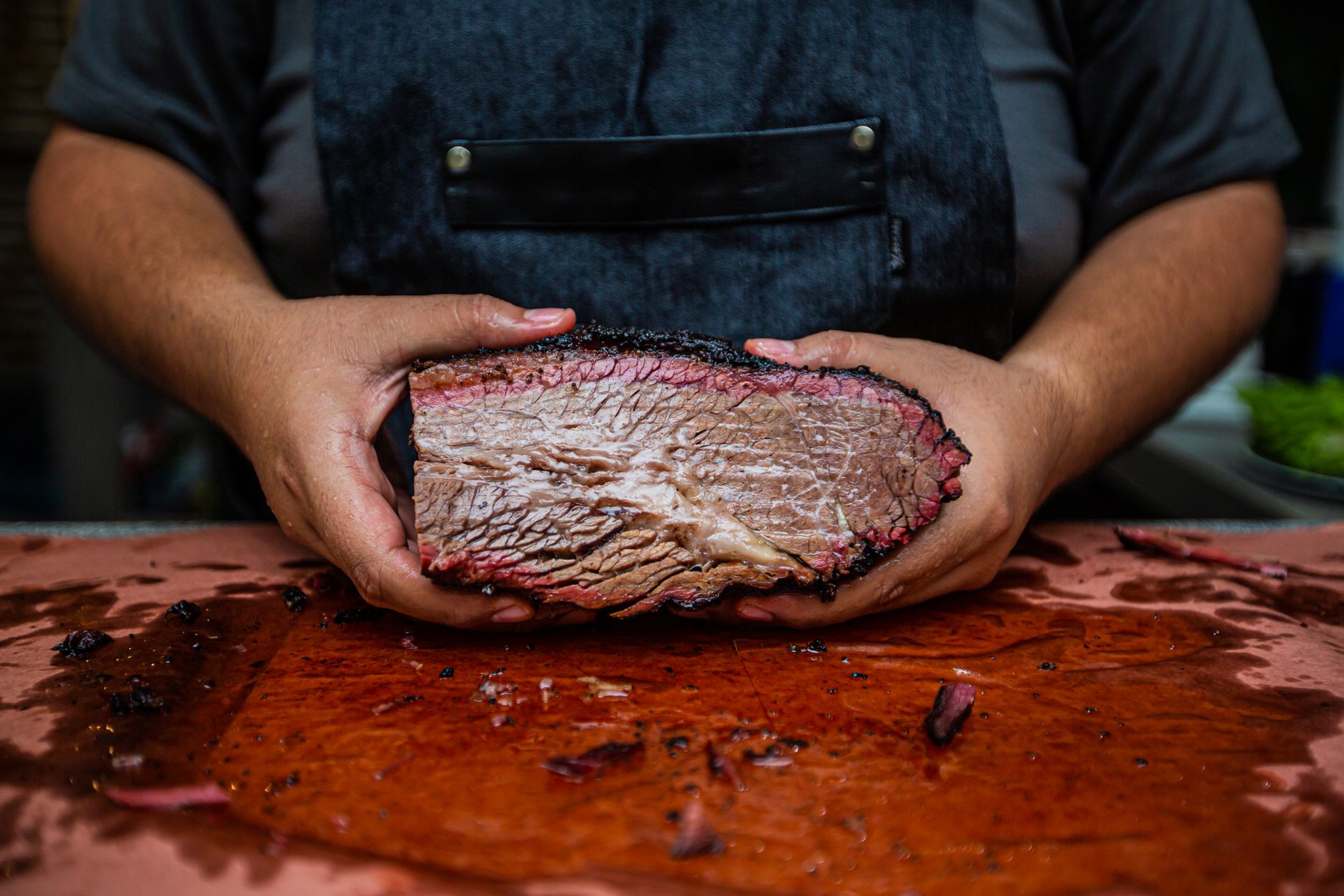 Slices of smoked brisket on a white plate served with side salad