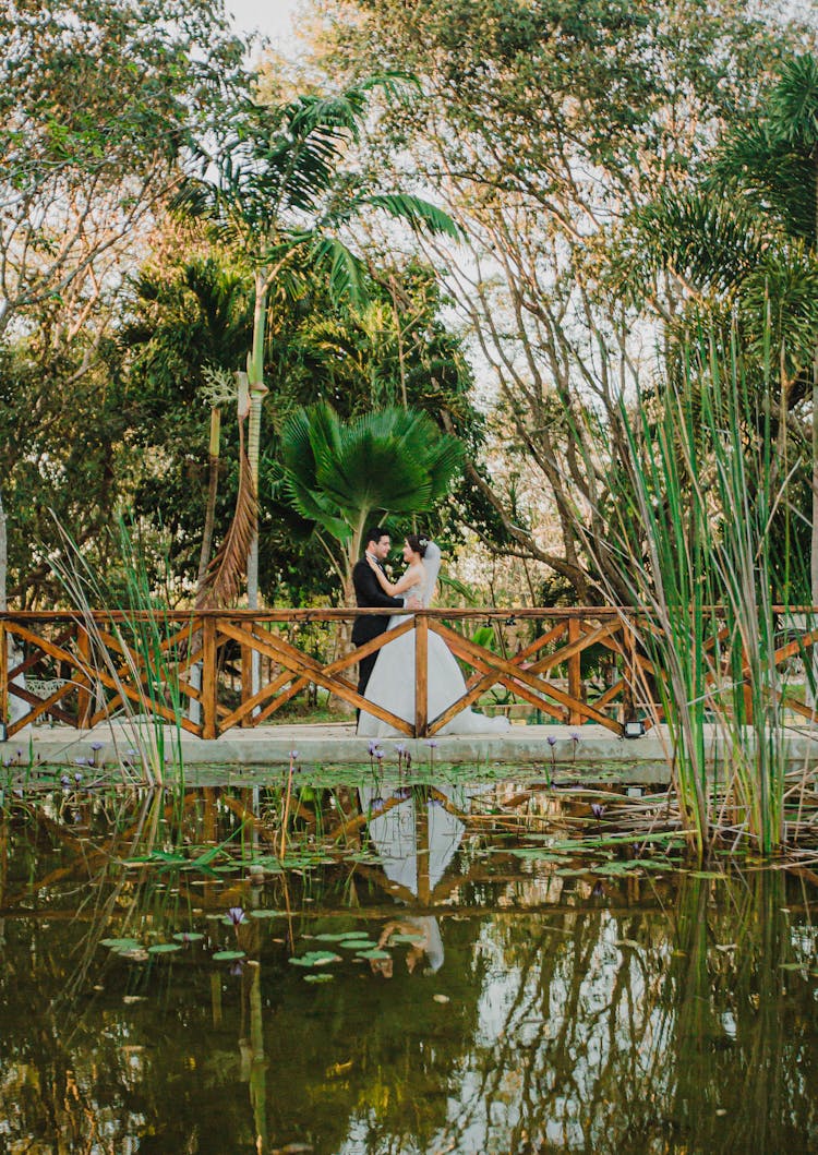 A Newlywed Couple Standing Near A Pond