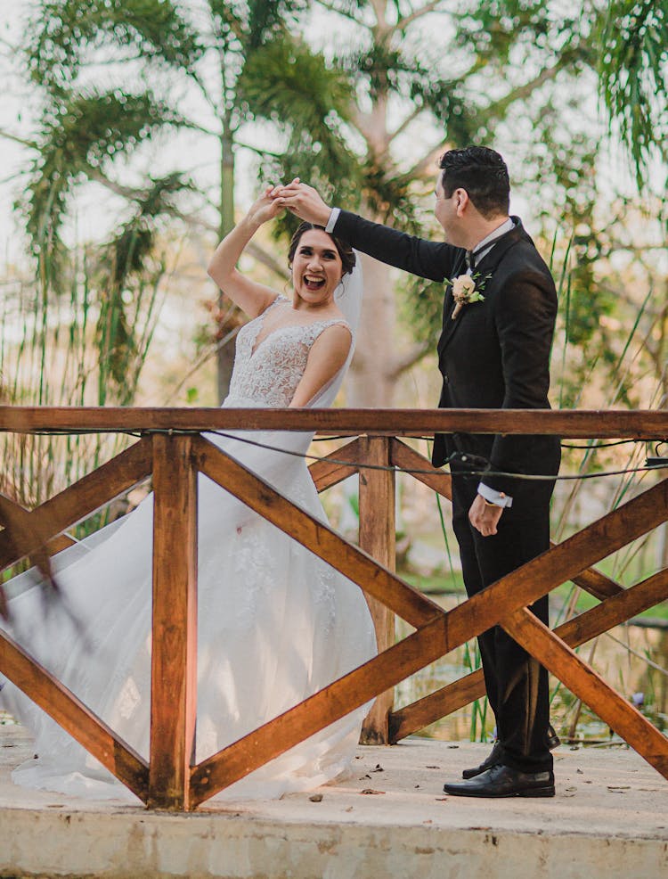 Man In Black Suit And Woman In White Wedding Dress Dancing On Concrete Bridge 