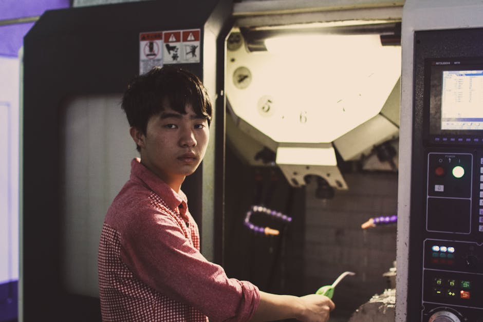 A young technician working on an industrial machine indoors. Dim lighting adds to the atmosphere.