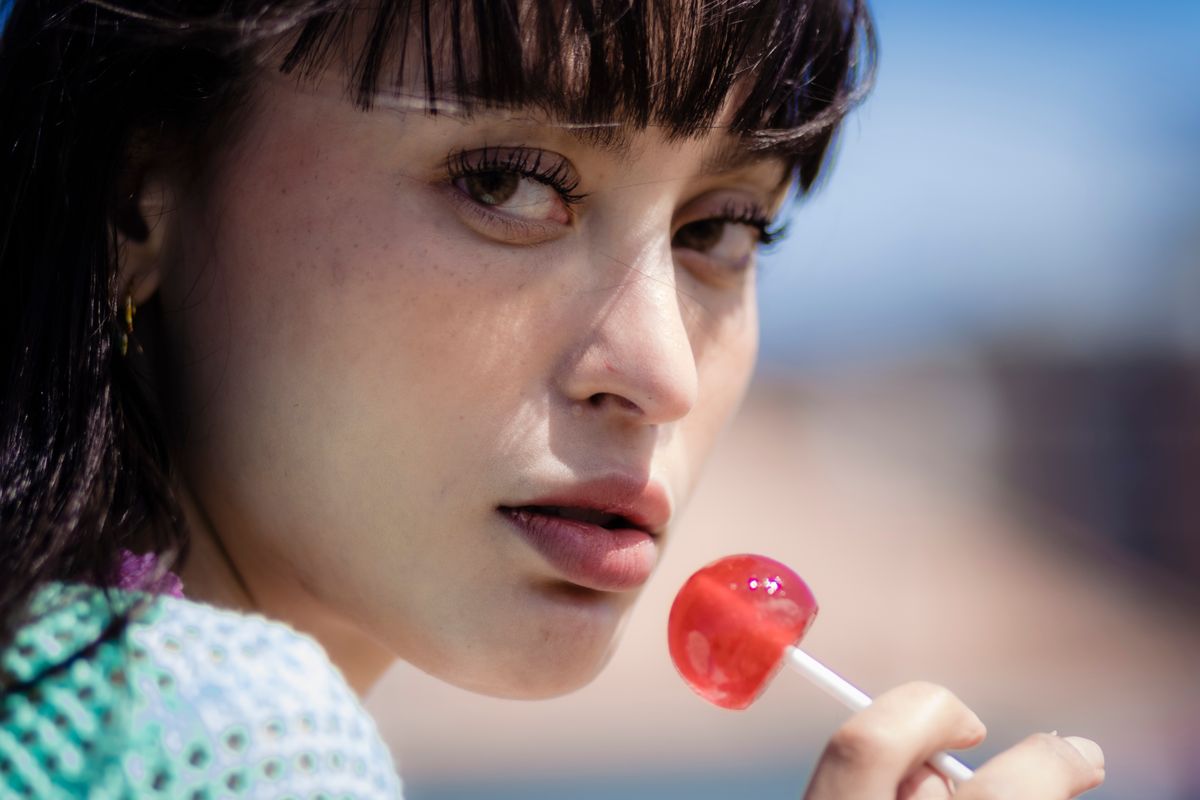 Close-up of a woman enjoying a red lollipop outdoors on a sunny day.