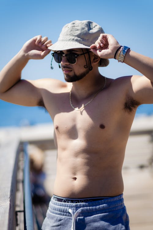 A Shirtless Bearded Man Wearing a Bucket Hat