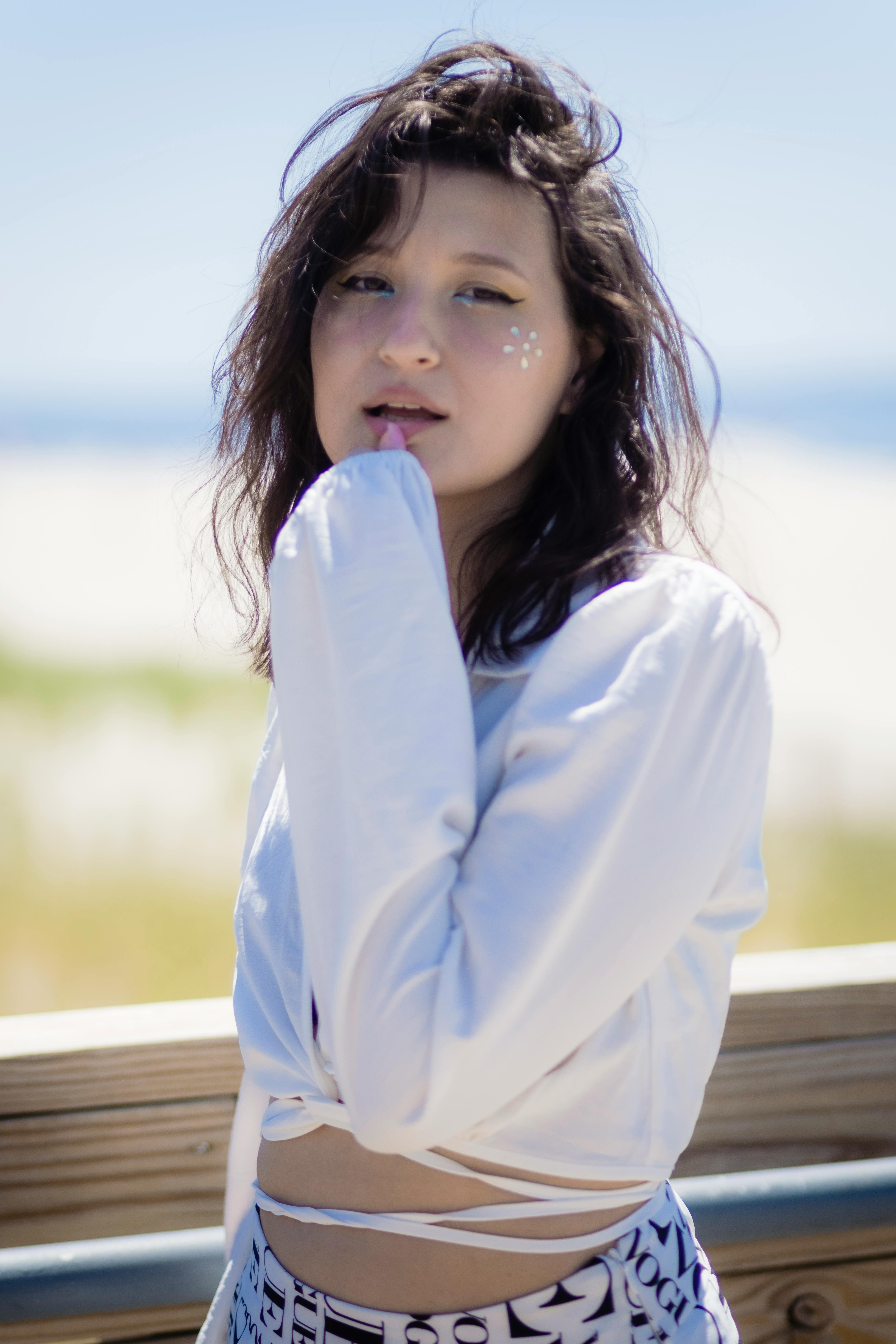 A Woman with Face Jewels Wearing a White Long Sleeved Top · Free Stock