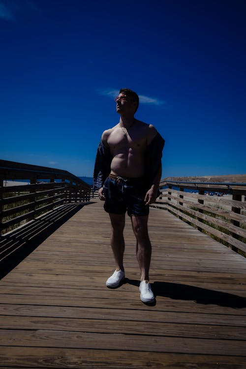 Shirtless Man Standing on Pier