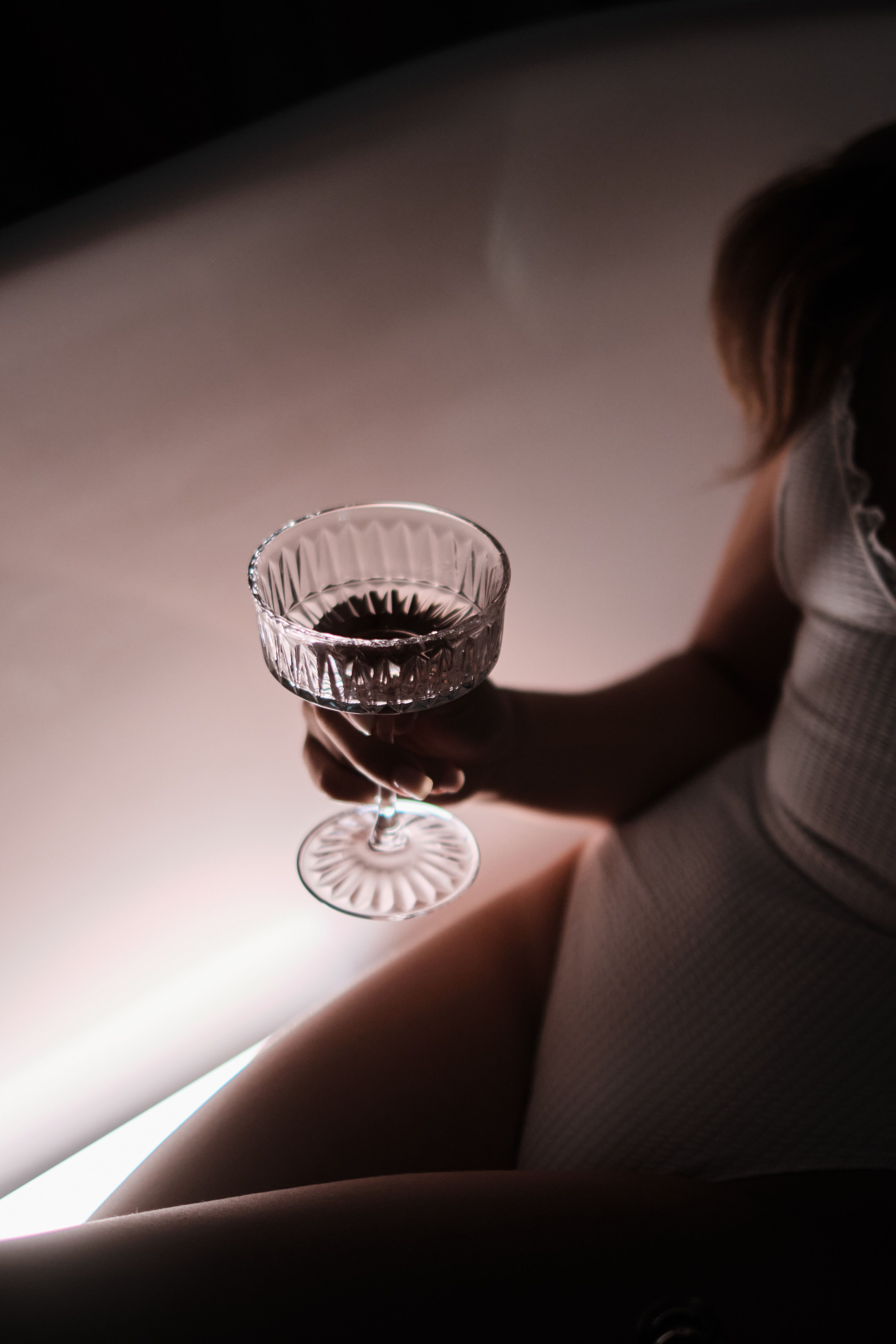 Close-up of a woman holding a wine glass, creating a warm, intimate scene with soft lighting.