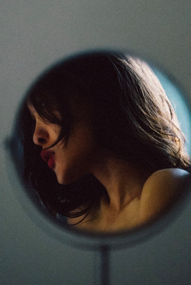 Reflection Of Young Woman Profile In Round Mirror