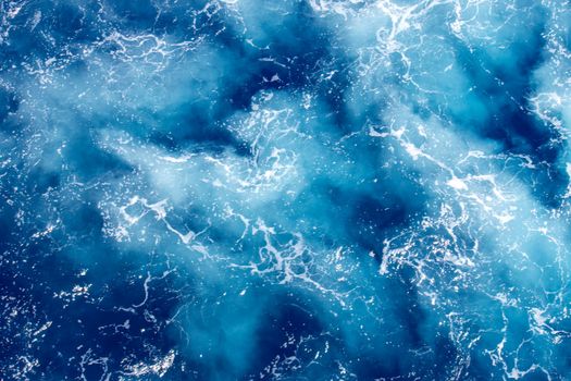 Aerial view of vibrant ocean waves creating stunning patterns of white seafoam against deep blue water.