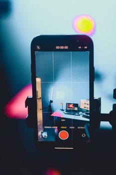 Close-up of a smartphone recording a vibrant creative studio setup with colorful lights.