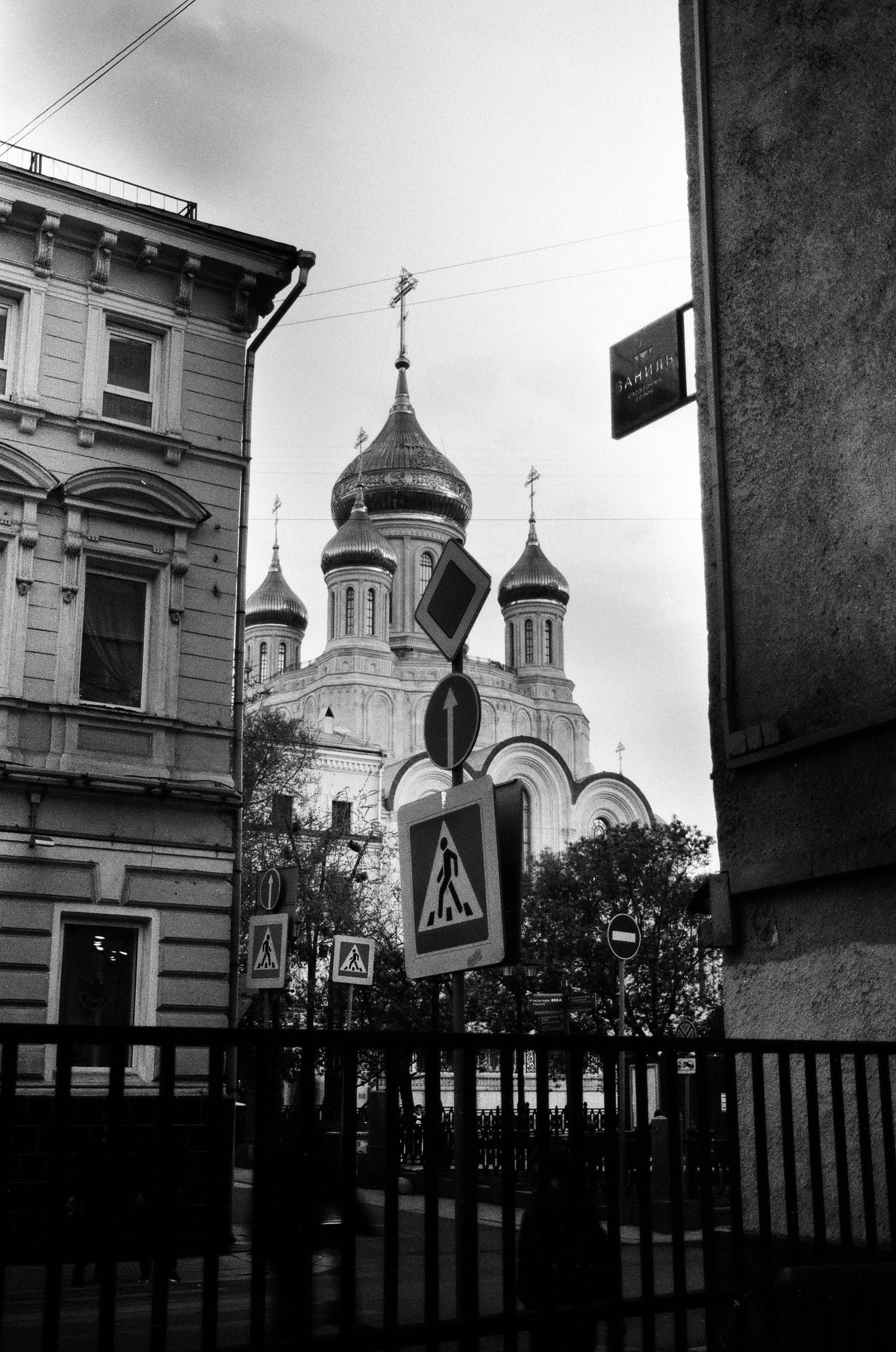 Black and white image capturing a historic church and street signs in an urban setting.
