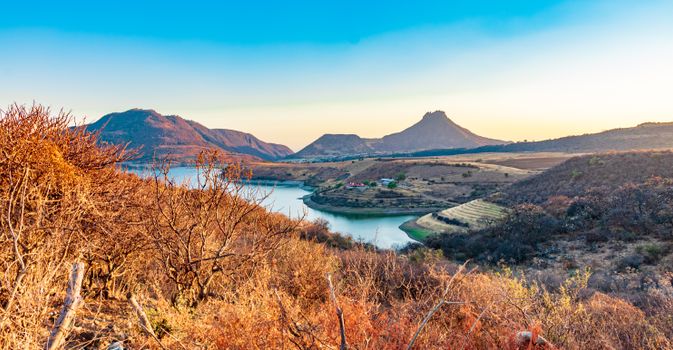 Beautiful view of a lake surrounded by hills and mountains in Zitácuaro, Mexico during sunset.