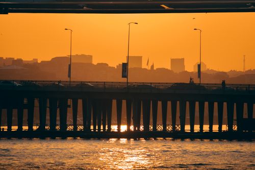 Free Captivating sunset view over a bridge in Istanbul with silhouettes of buildings and an orange sky. Stock Photo