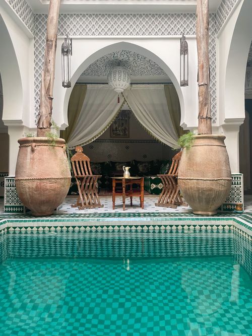 Free Beautiful Moroccan riad interior with pool, pottery, and luxurious seating in Marrakech. Stock Photo