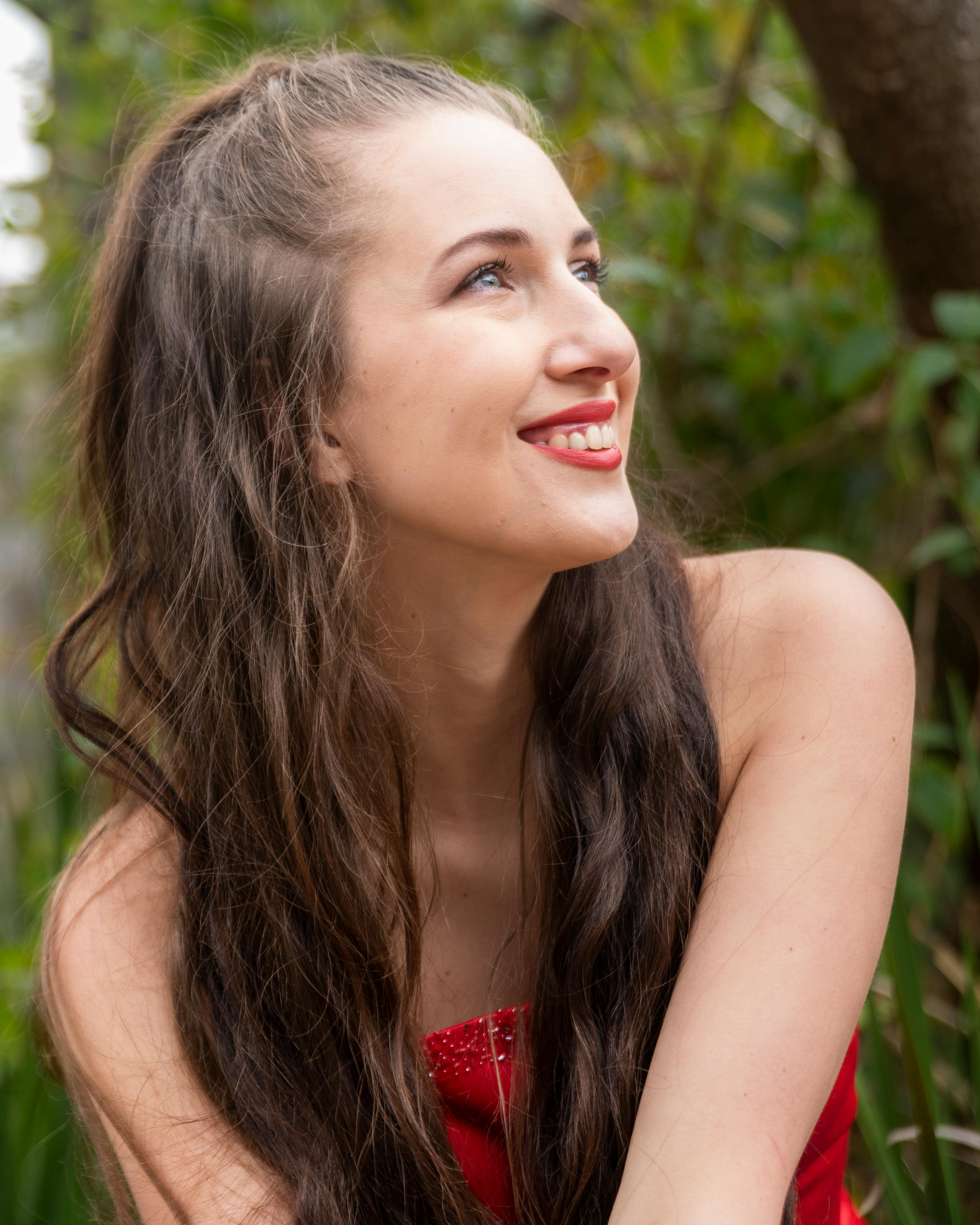 Portrait of a young woman smiling joyfully in a natural setting.