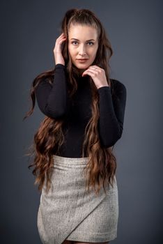 Portrait of a young woman with long hair posing in a studio setting.
