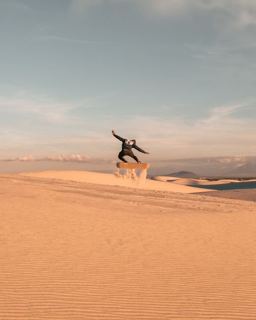 Captivating sandboarding action against Cape Town's golden dunes and clear sky.