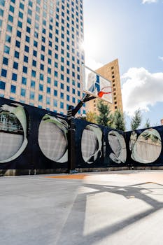 A vibrant outdoor basketball court in downtown Oakland, framed by skyscrapers and sunlight.