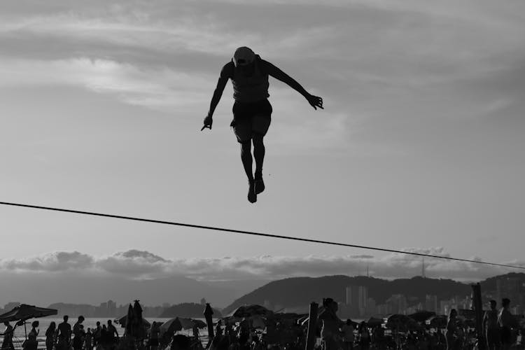 Grayscale Photo Of Person Jumping Over The Rope 