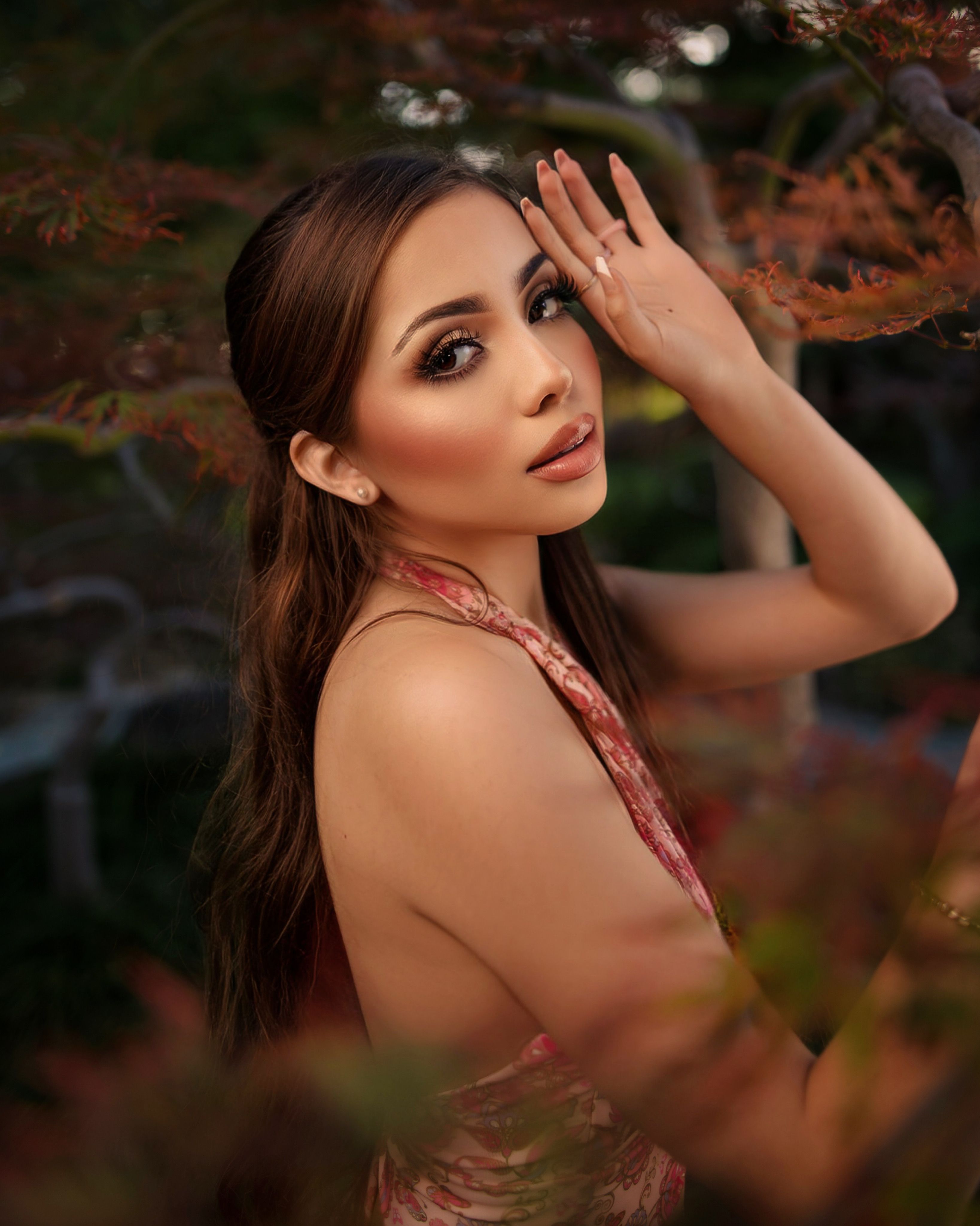 Artistic portrait of a woman with elegant pose surrounded by autumn leaves.