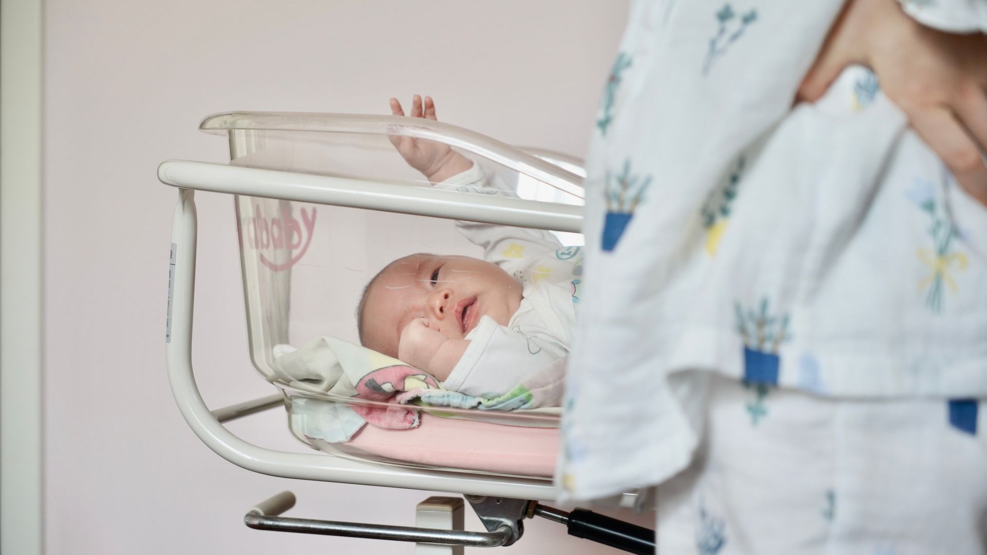 Modafinil for New Parents: Unlocking Energy and Focus A tender scene of a newborn baby lying in a hospital bassinet with the mother standing close by — modafinil for new parents