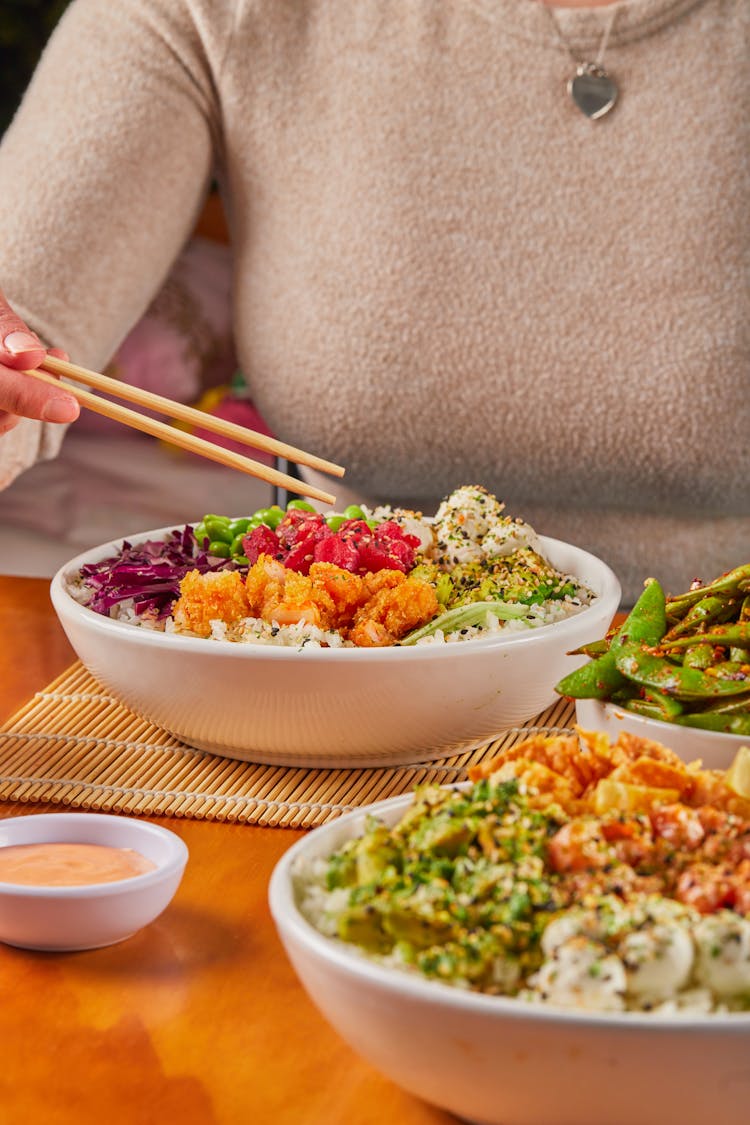 Close-up Of People Eating Asian Food In Bowls