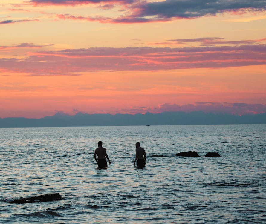 Silhouette of People in the Ocean during Sunset