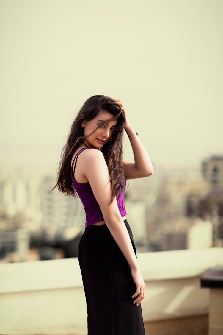 A Woman In Purple Tank Top And Black Skirt Looking Over Shoulder