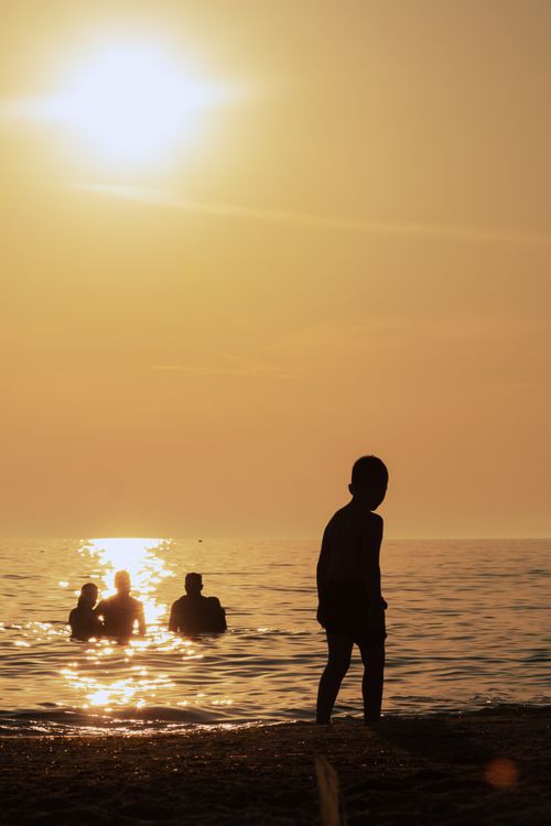 Free Peaceful beach scene with silhouettes of people enjoying a sunset in Durrës, Albania. Stock Photo