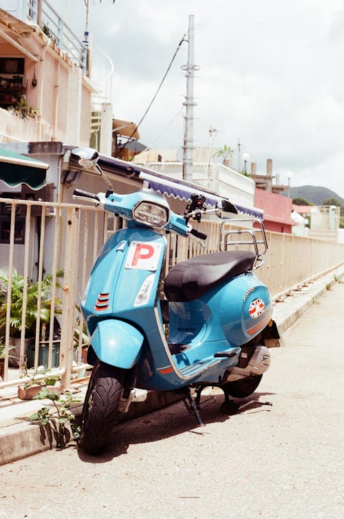 Blue Moped Vespa Scooter Near Metals Fence 