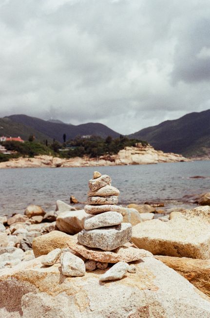 Stacked stones by the sea with mountains in the background, Hong Kong Island.