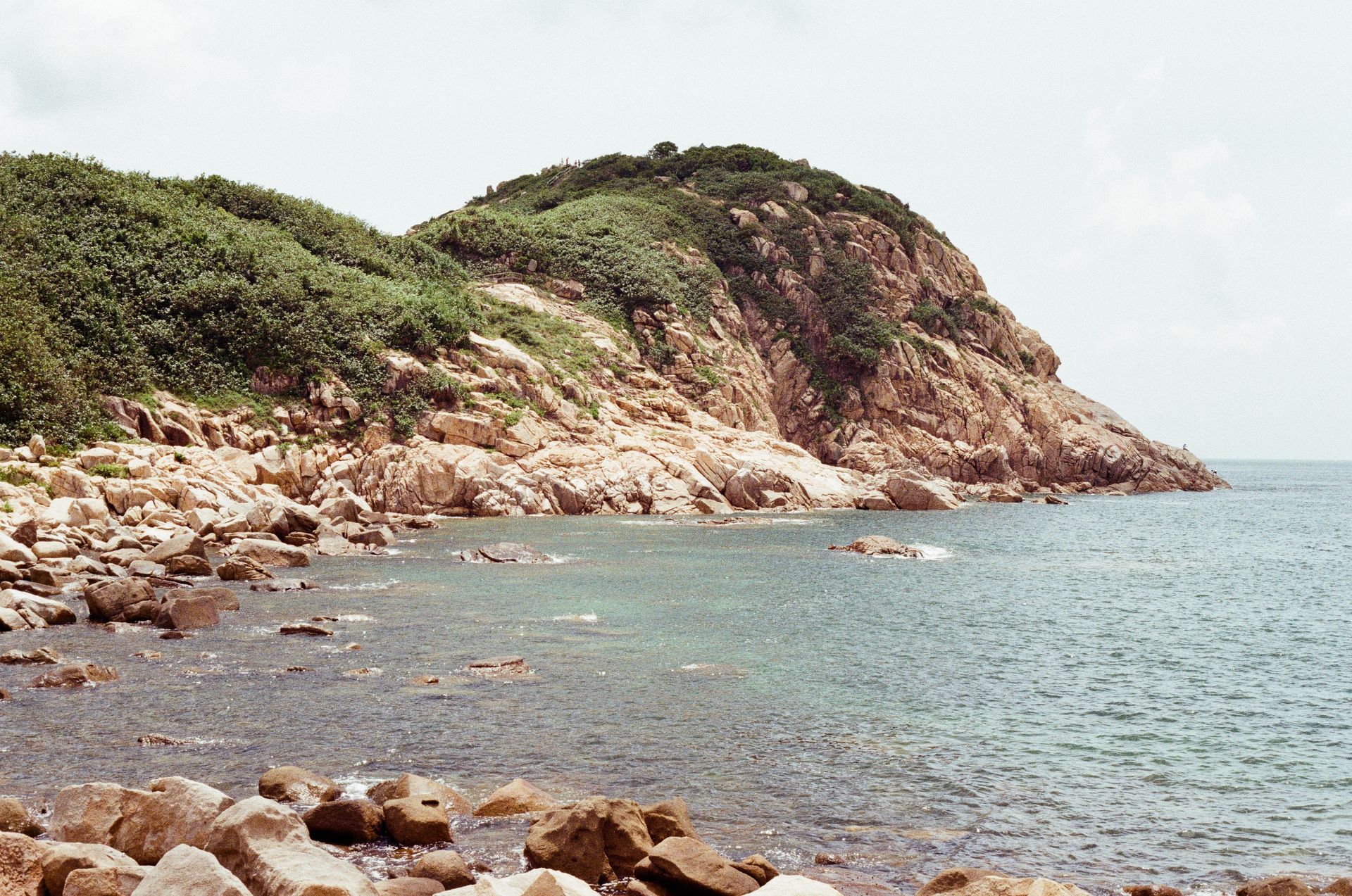 Scenic view of the rocky shoreline and lush greenery on Hong Kong Island coast.