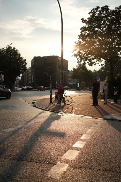 Free Street scene in Hamburg with bicyclist and pedestrians, captured at sunset, highlighting urban life. Stock Photo