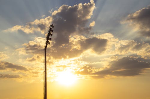 Silhouette Photo of Light Tower Under Sunrays