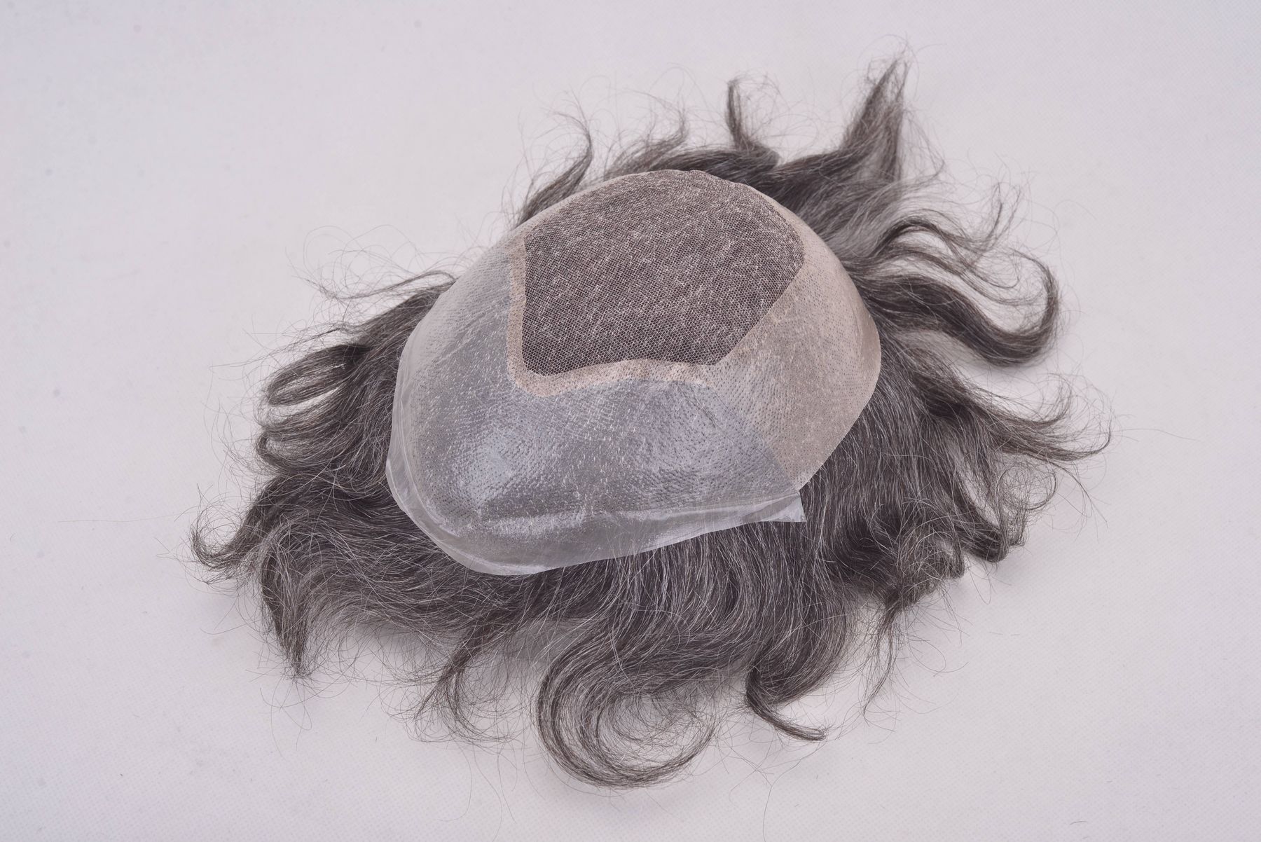 A men's hair system: fine dark and grey hair on a lace base
