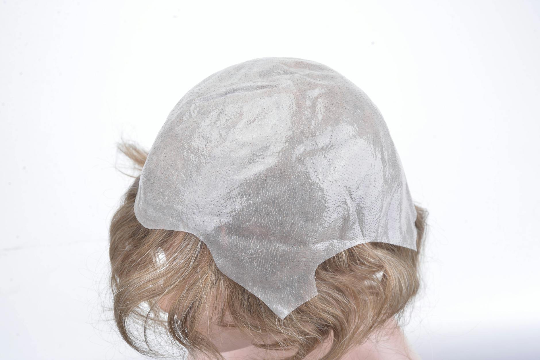 Close-up of blonde hair covered with a translucent plastic cap on a mannequin head.