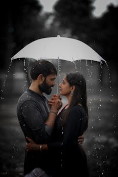 A romantic couple embracing under an umbrella in the rain, capturing love and togetherness.