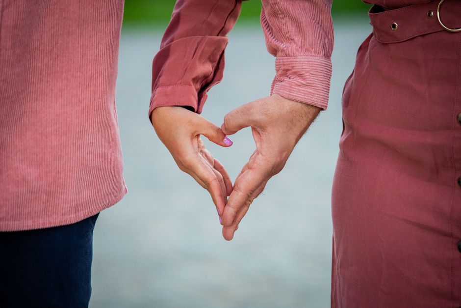 Close-up of a couple forming a heart shape with hands symbolizing love and connection.