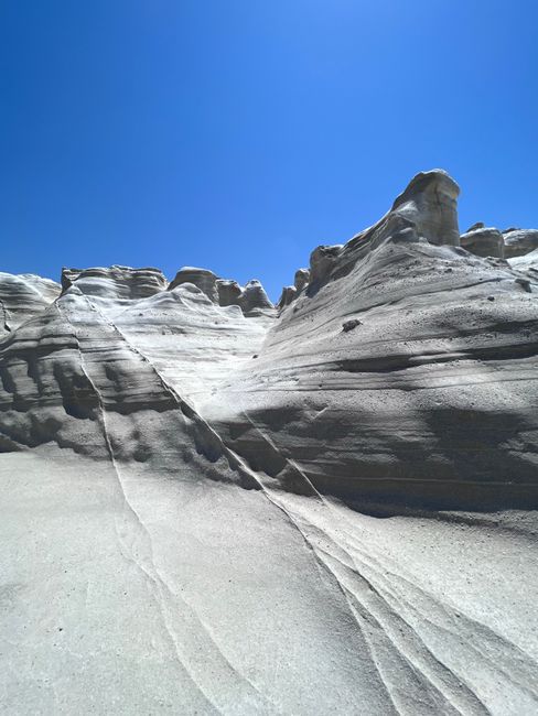 Dramatic white geological formations under a clear blue sky in Milos, Greece.