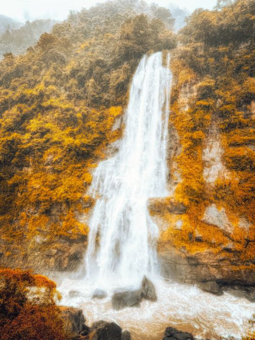Free Breathtaking waterfall cascading through vibrant autumn foliage in a serene forest landscape. Stock Photo