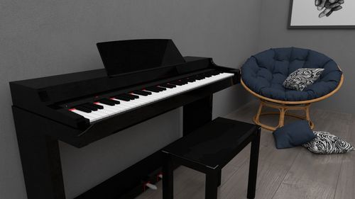 Free A stylish room featuring a black piano, stool, and a cozy cushioned chair with decorative throw pillows. Stock Photo