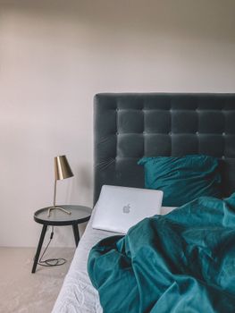 A modern bedroom with a laptop on the bed beside a stylish lamp, perfect for work-from-home scenarios.