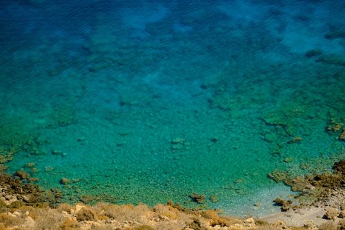 Free Stunning aerial shot of clear blue waters and rocky shoreline, perfect for travel and nature enthusiasts. Stock Photo