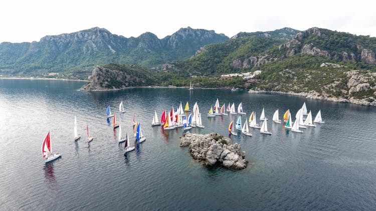 An Aerial Photography Of Sailing Boats On The Sea Near The Mountain