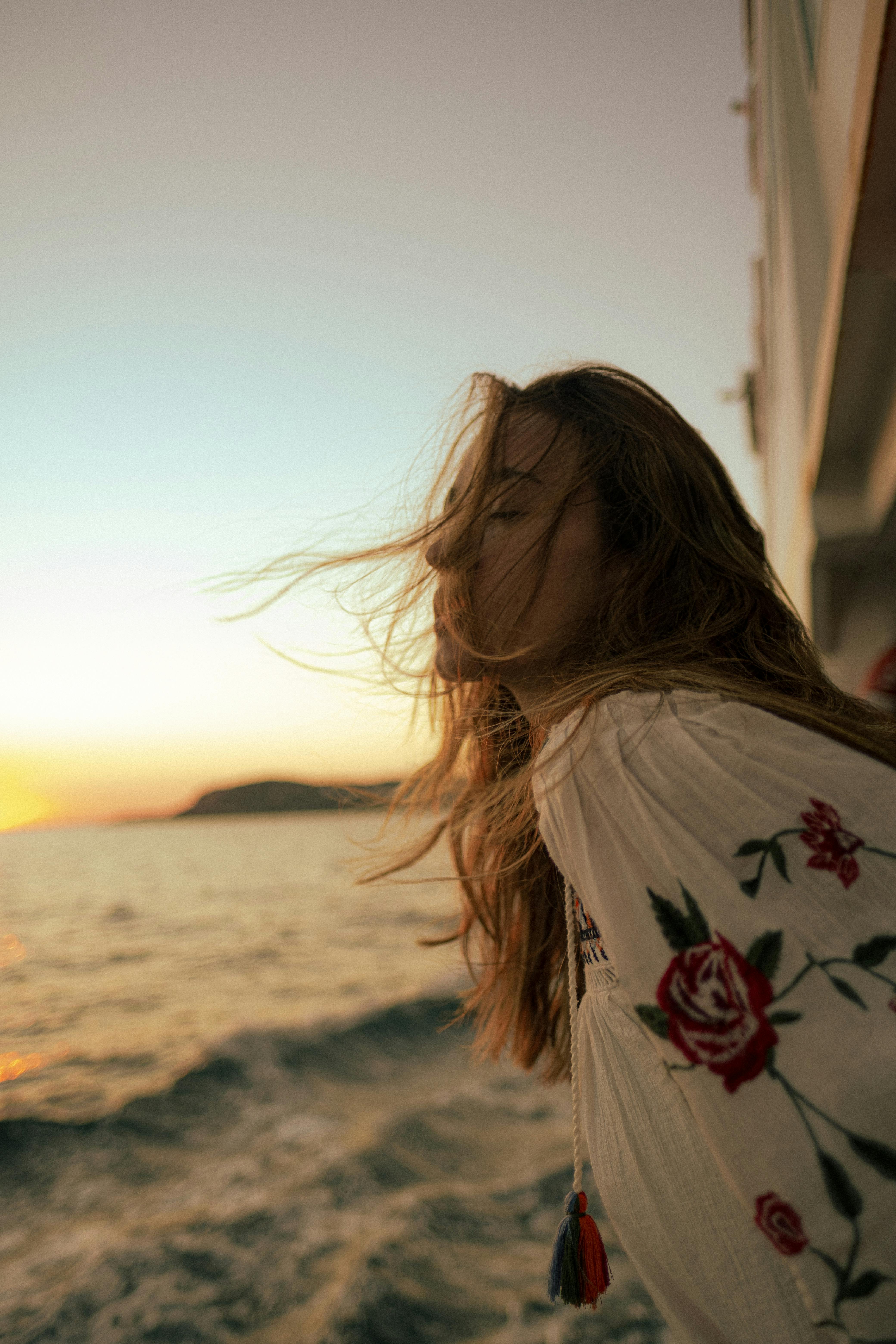 A woman with long hair embraces the breeze and sunset by the sea in İstanbul, Turkey.
