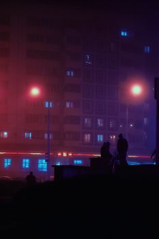 Silhouettes walking at night under street lamps, vibrant city backdrop.