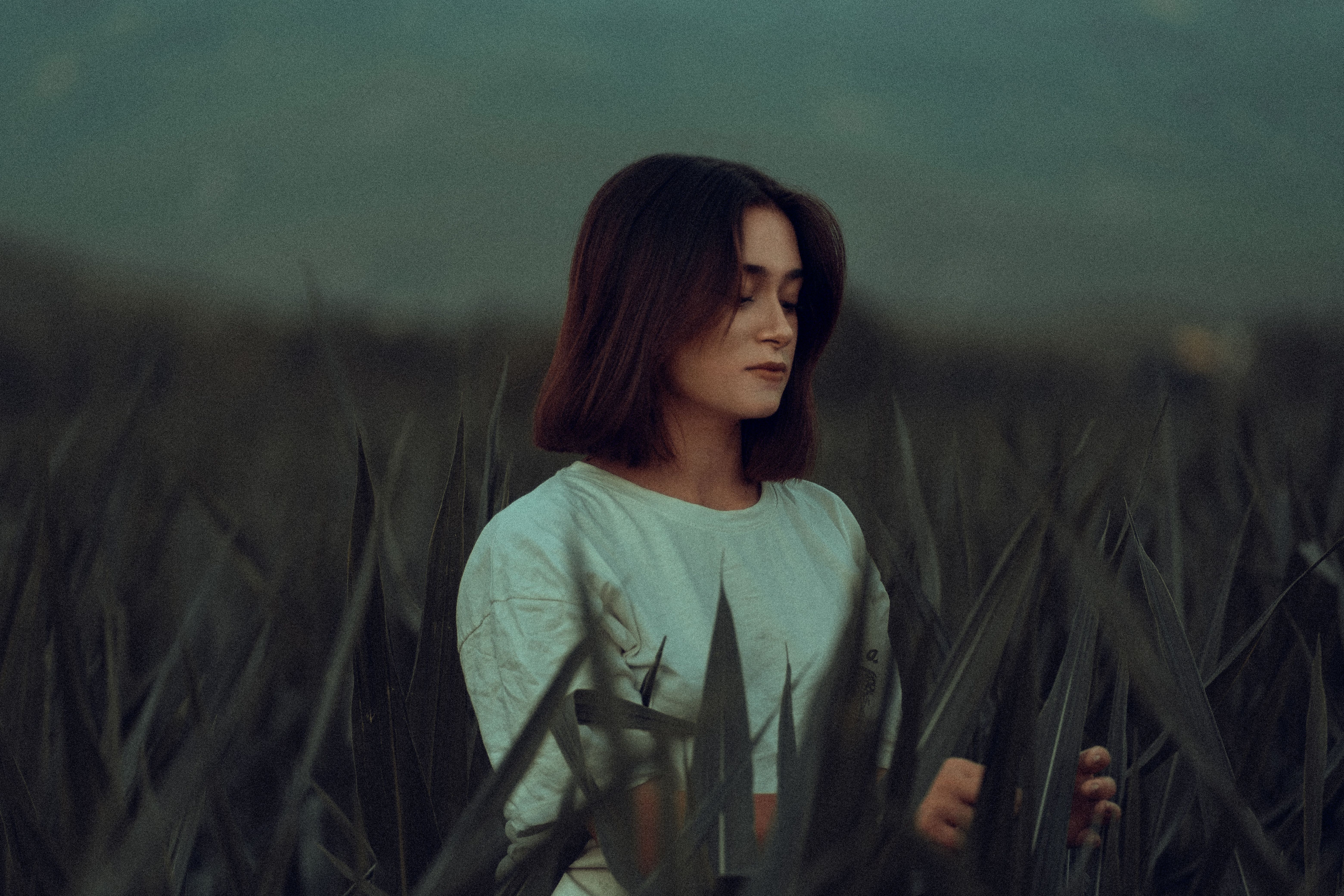 A serene moment captured as a woman meditates in a lush green field.