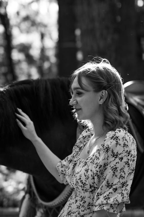 Grayscale Photo of a Woman Holding a Horse